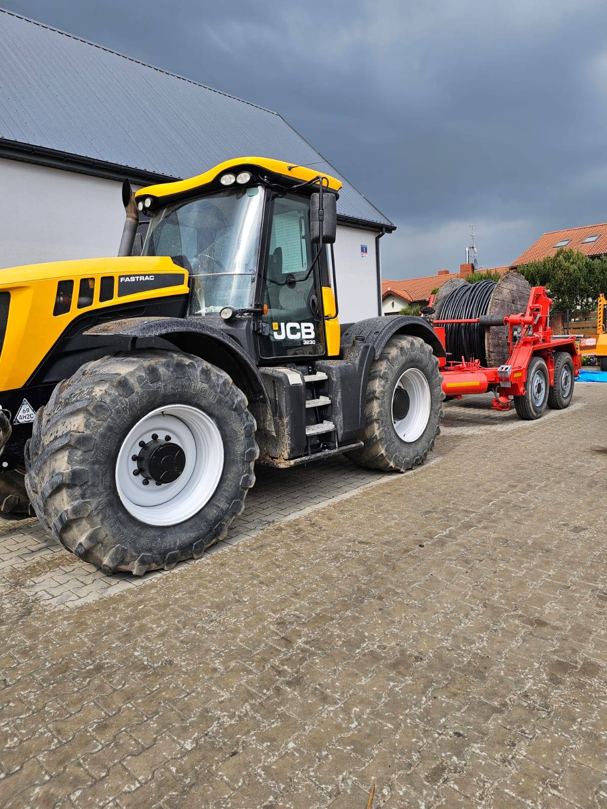 Ciągnik JCB Fastrac z przyczepą do bębnów kablowych i nawiniętym kablem