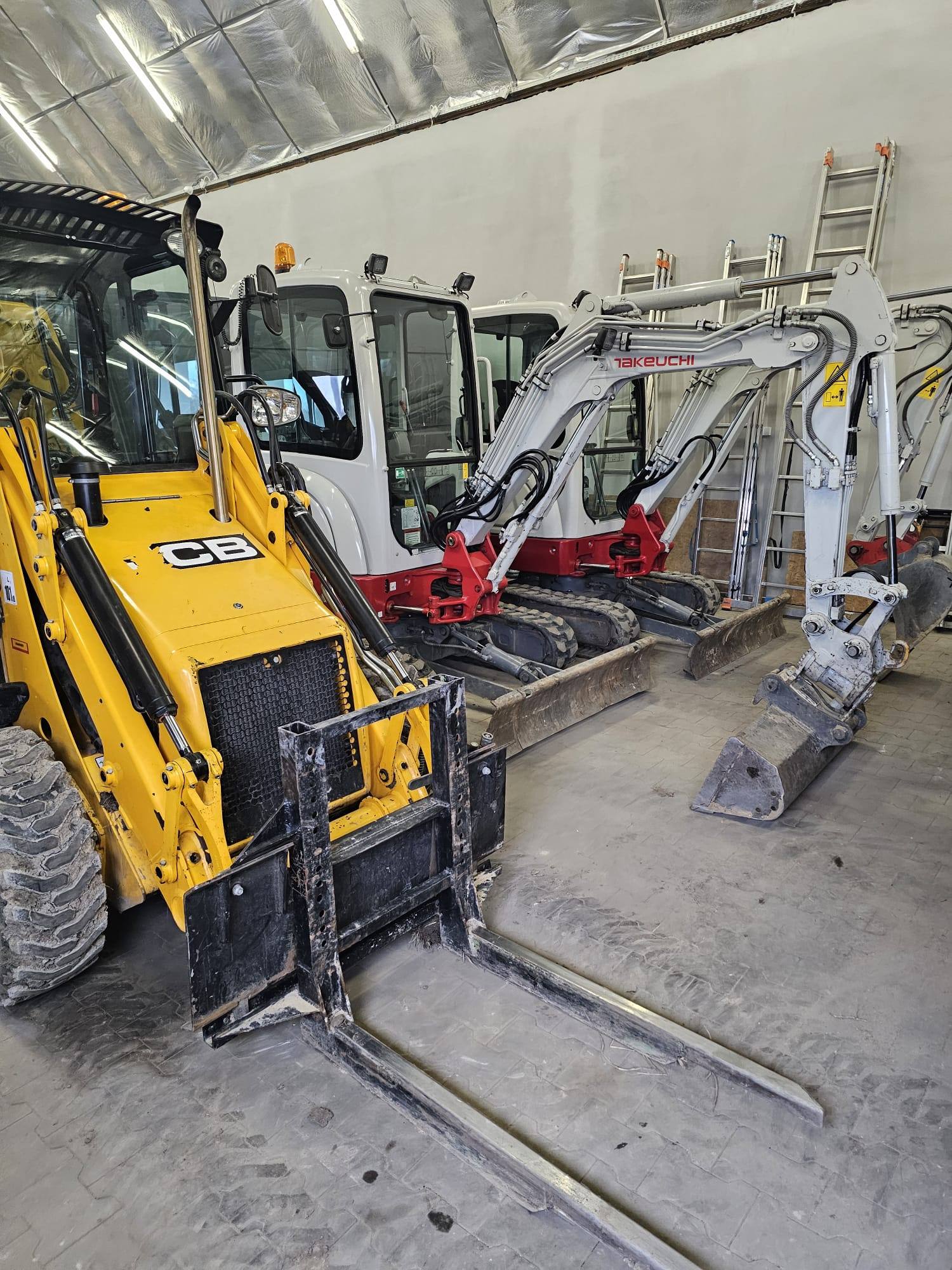 Koparka JCB i minikoparki Takeuchi w hali sprzętowej firmy